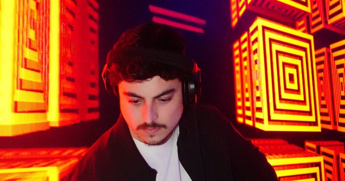 DJ OTEO performing inside a red-lit LED cube room